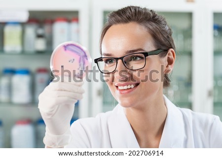 Woman in laboratory looking at Petri plate, horizontal