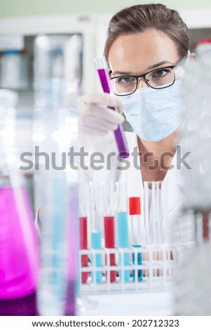 Lab technician in protective mask holding a test tube