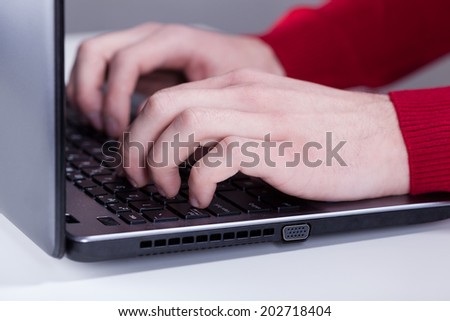 A closeup of caucasian male hands typing on laptop\'s keyboard