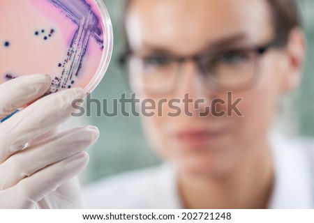 Microbiologist holding a Petri dish with bacteria, horizontal