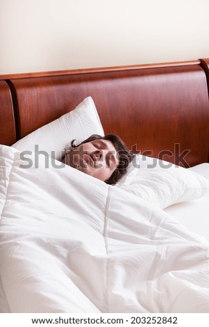 Young man sleeping alone in white bedding