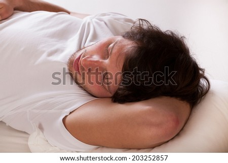 Young handsome man in white pajama sleeping on pillow