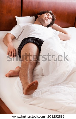 Young tired man sleeping in his bed like a log