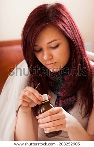 Young woman with flu drinking cough syrup