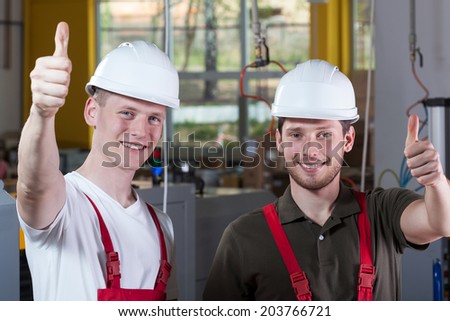 Happy factory workers giving thumbs up sign