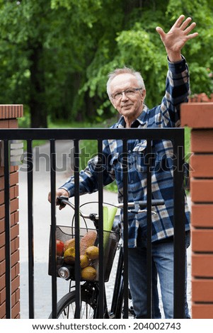 Smiling male cyclist in flannel shirt waving hello