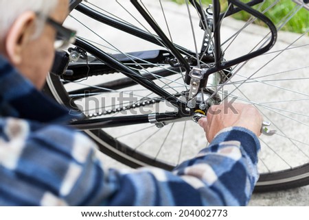 Close-up of a senior man tightening the bolts on a bicycle wheel