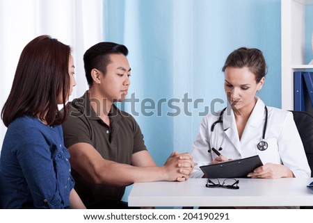 Asian couple during visit at doctor\'s office, horizontal