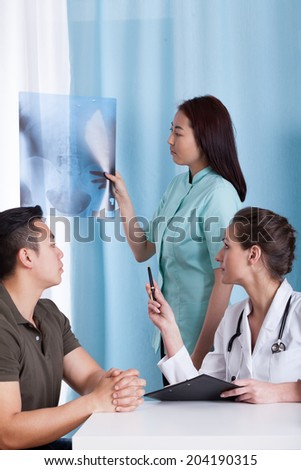 Caucasian female doctor analyzing x-ray of her Asian patient