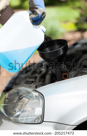 Close-up of adding windshield washer fluid on a car