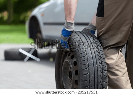 Close-up of a man rolling a spare wheel