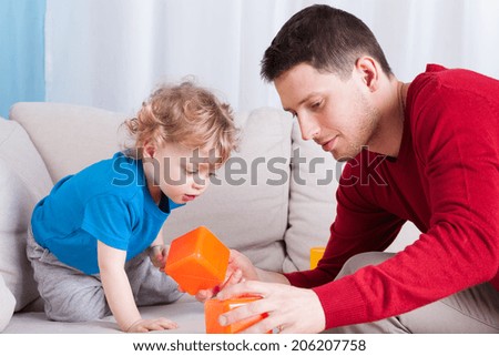 Man and little boy playing with toys together