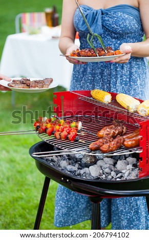 Woman taking grilled dishes to eat on garden party