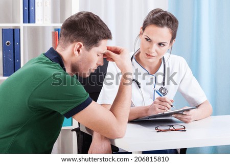 Young man sitting on medical visit with strong headache