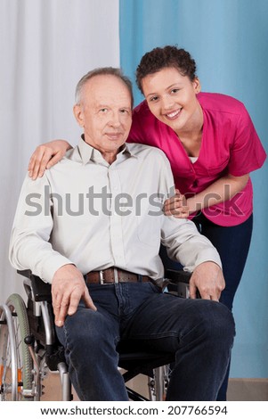 Nurse standing by the disabled in a wheelchair and smiling