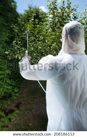 Man spraying tree in a orchard, vertical