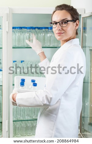 Lab assistant with empty glass bottle, vertical