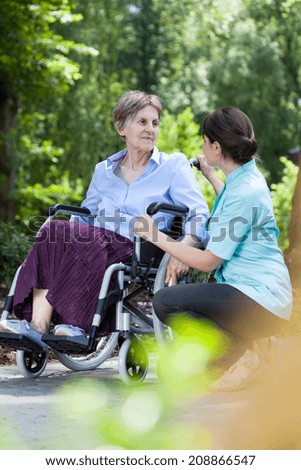 Elderly woman in a wheelchair with a nurse spends time in the garden