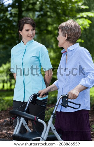 Elderly woman walking with a walker and with nurse