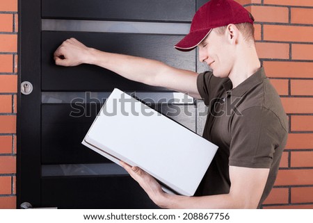 Young delivery man knocking on the client door