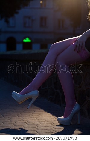 Woman in high heels sitting on brick fence