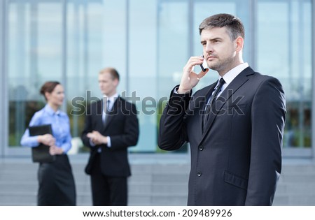 Businessman calling on mobile phone outdoors, horizontal