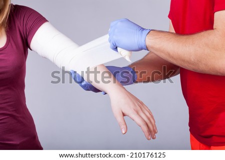 Rescuer bandaging upper limb of young woman