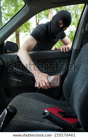 Burglar taking wallet from somebody\'s car, vertical