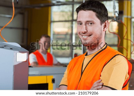 Smiling industrial worker standing with arms crossed at factory