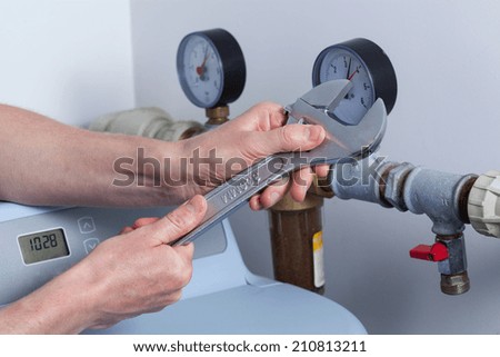 Man\'s hands with wrench repairing pressure gauge