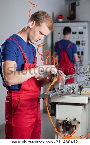 Vertical view of a laborer repairing factory machine