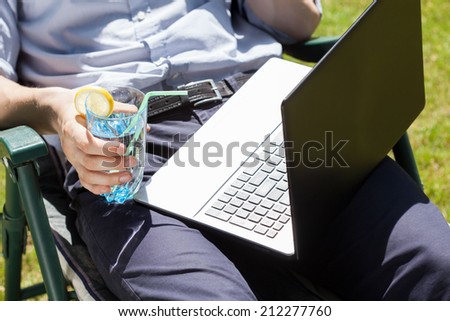 Businessman working in the garden on a laptop and drinking
