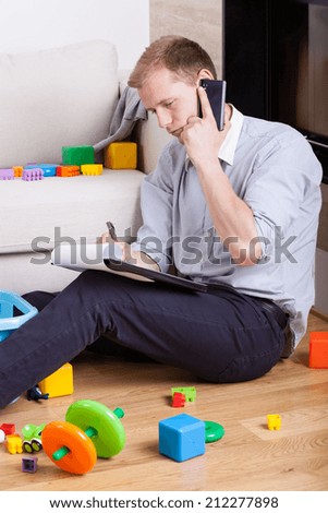 Multifunctional dad sitting on the floor and talking on the phone
