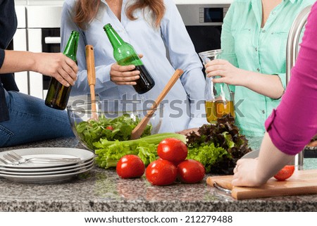 Young people having fun drinking beer and preparing food at home