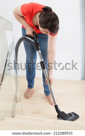 Close-up of a young woman vacuuming stairs