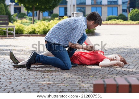 Man trying to help unconscious woman on the street