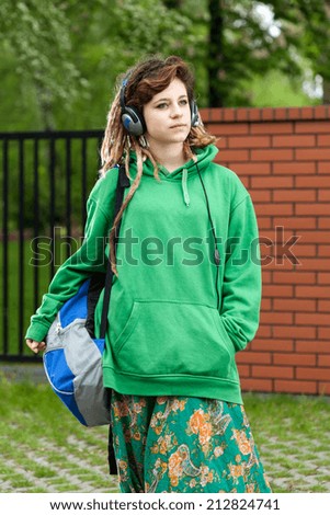Vertical view of a teenage girl with backpack listening to music