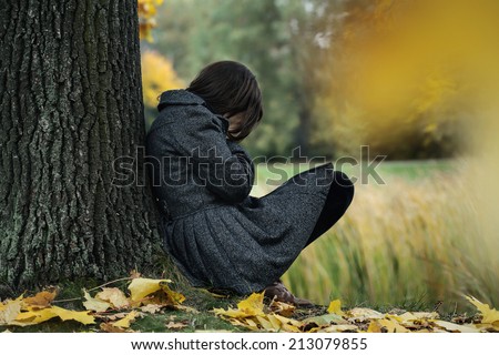 Woman sitting on the ground and crying in the park