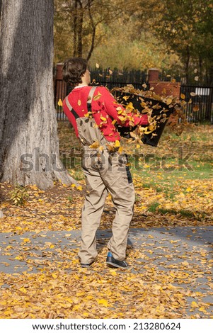 A gardener carring a black box full of autumn leaves