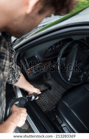 Man dusting interior of the car, vertical
