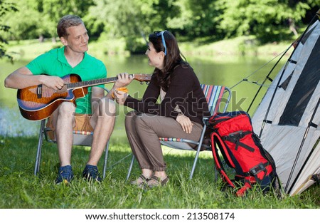 Man playing guitar song for woman on camping