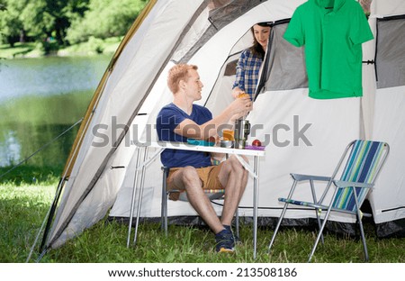 Young couple making breakfast in front of tent