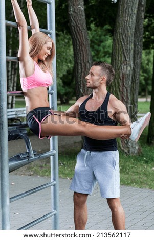 Man helps woman with training in a park