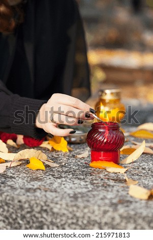 Young widow lighting a candle on the husband grave
