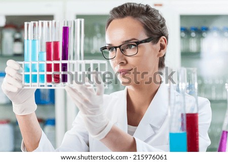 Woman analyzing test tubes with liquid, horizontal