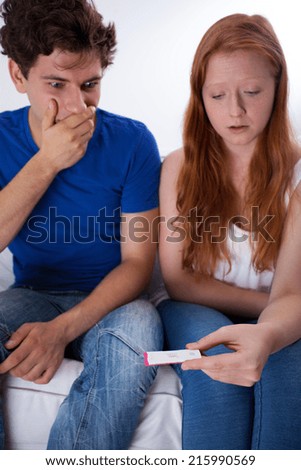 Frightened young couple with positive pregnancy test
