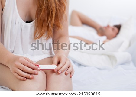 Woman with positive pregnancy test in bed