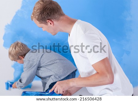 Father looking at his son during wall painting, horizontal
