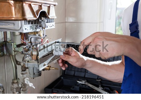 Repairman fixing a gas water heater with a screwdriver