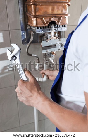 Repairman fixing a gas water heater with a wrench